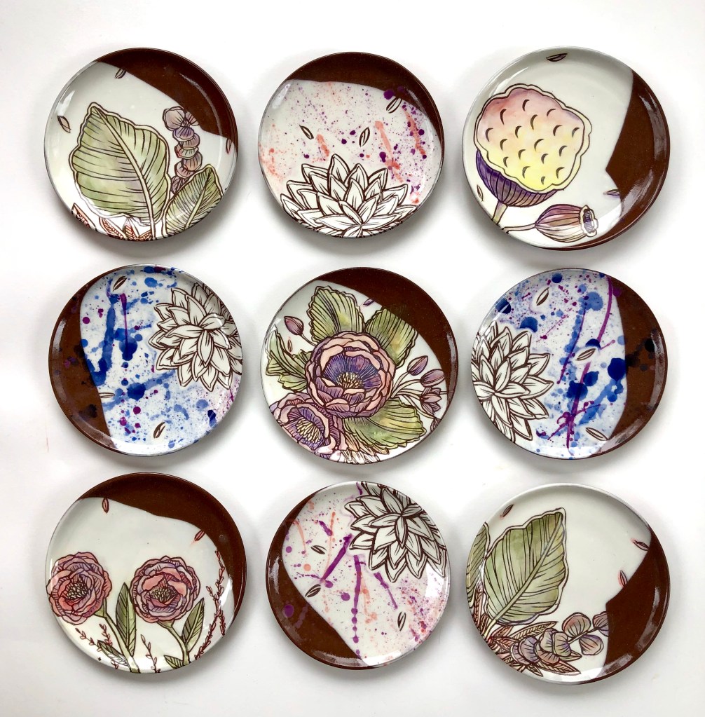 Ceramic plates with white and brown glazed backgrounds with floral designs on top of it.